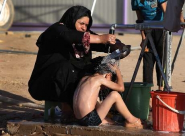 22 de junho - mulher iraquiana banha seu filho em um acampamento para deslocados iraquianos que fugiram de Mossul e outras cidades tomadas pelos insurgentes do Estados Islmico e do Levante  Foto: AP