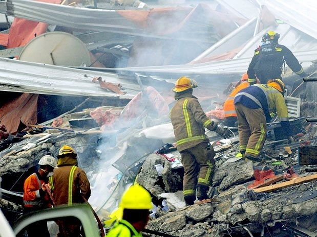 Bombeiros sobem em destroços de prédio para procurar por vítimas, em Christchurch