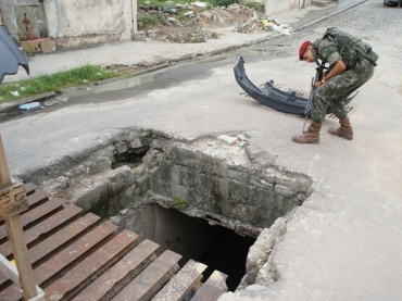 Militar recolhe partes de carroceria perto da cratera usada para fuga de criminosos 