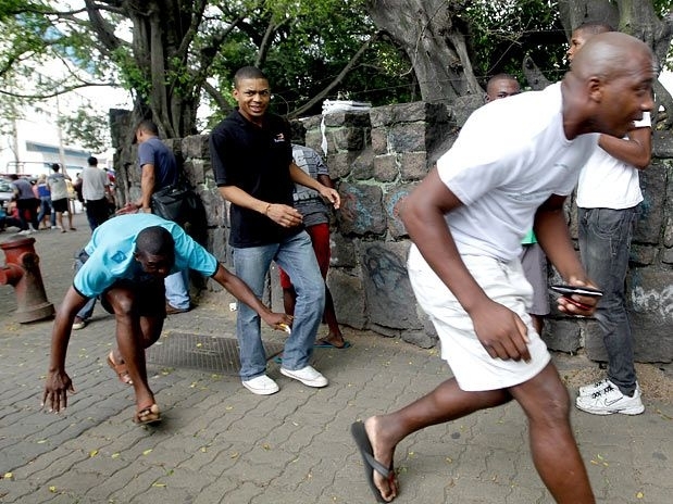 Homens tentam se proteger de balas perdidas de confronto na Vila Cruzeiro