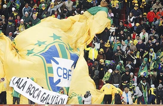 Torcedores com a bandeira do Brasil e com um cartaz do 