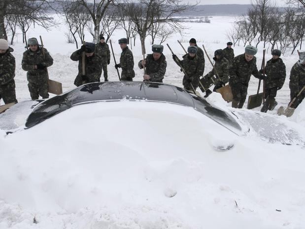 Trabalhadores dos servios de emergncia tentam retirar um carro que ficou soterrado na cidade de Brody