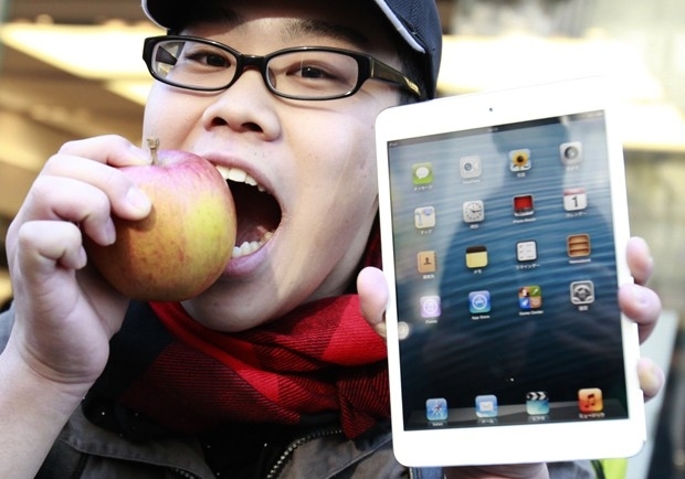 F Koudai Taguchi morde uma ma enquanto mostra seu iPad mini recm comprado em uma loja de Tquio
