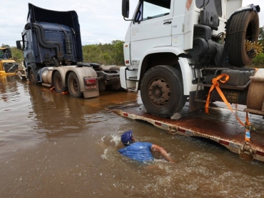 Homem nada ao lado de carretas na BR-364, inundada pelo Rio Madeira