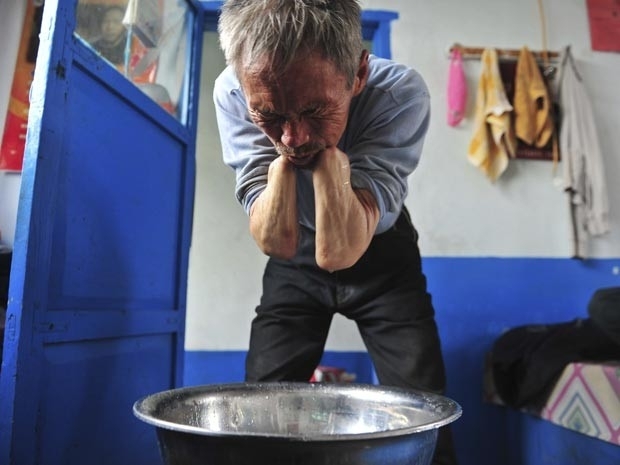 Sem as prteses, Sun Jifa lava o rosto