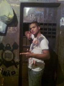 Simulando armas com os dedos, Leandro Martins da Silva, o Risadinha, posa no interior da cela