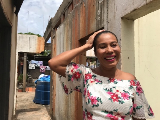 Cristiane em frente  casa onde morava, que hoje no tem mais telhado