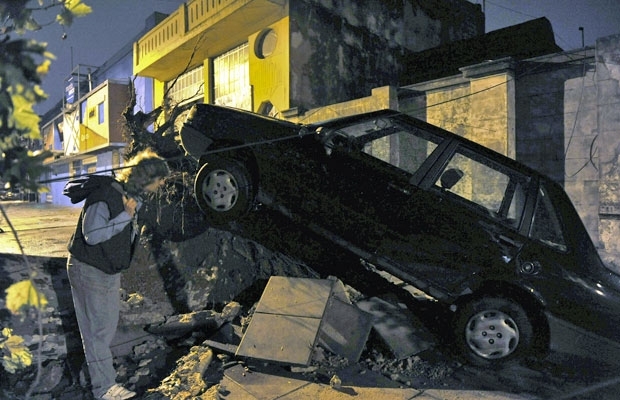 Homem observa automvel destrudo sobre calada em Buenos Aires, nesta quinta (5)
