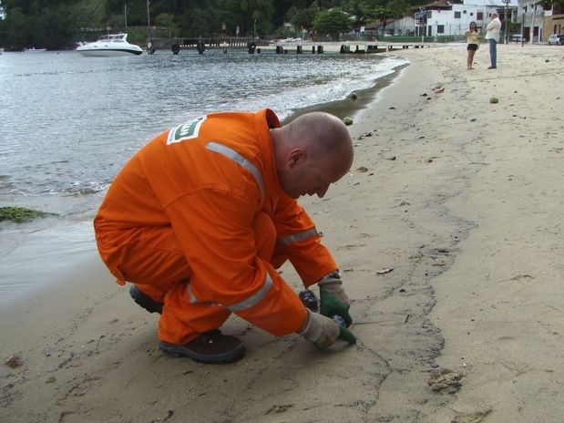 Tcnico coleta amostras de areia de praia atingida por vazamento de leo em Angra dos Reis