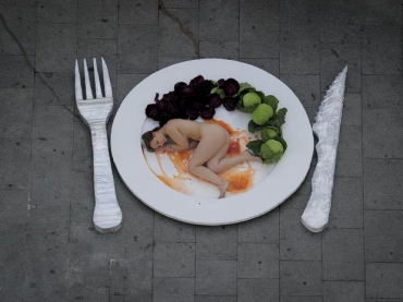 Ativista nua em um prato simula ser um peda�o de carne em frente a um mercado em Barcelona