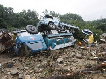 Sul-coreano caminha por veculos destrudos aps um deslizamento de terra em Seul, Coreia do Sul. Avalanches deixaram 17