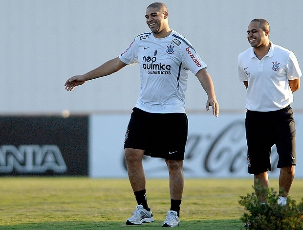 Adriano caminha no gramado do CT ao lado do fisioterapeuta Caio Mello