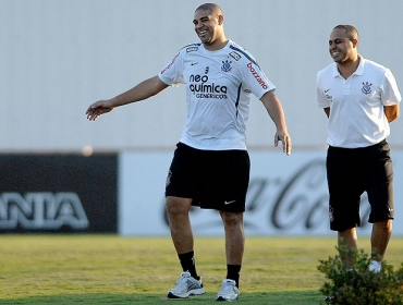 Adriano caminha no gramado do CT ao lado do fisioterapeuta Caio Mello