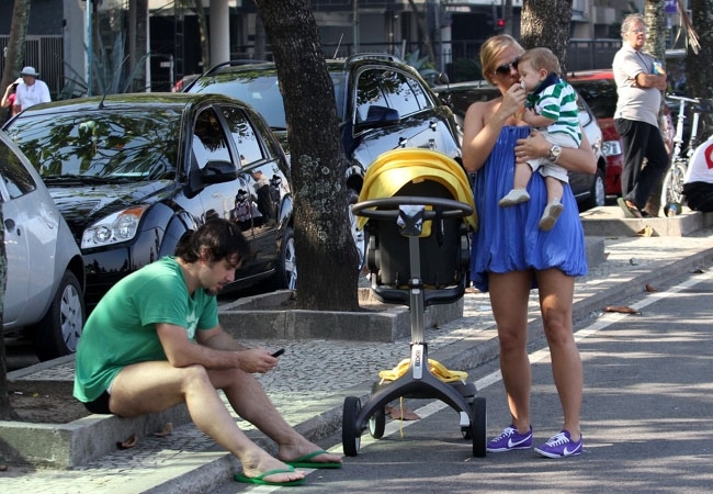 Alexandre Idice checa as mensagens no celular enquanto Adriane Galisteu paparicava o menino