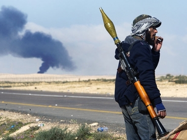 Rebelde lbio se posiciona nos arredores da cidade de Brega enquanto um alvo no identificado queima no horozonte