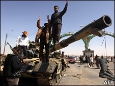 Rebeldes comemoram sobre tanque abandonado na cidade de Ajdabiya